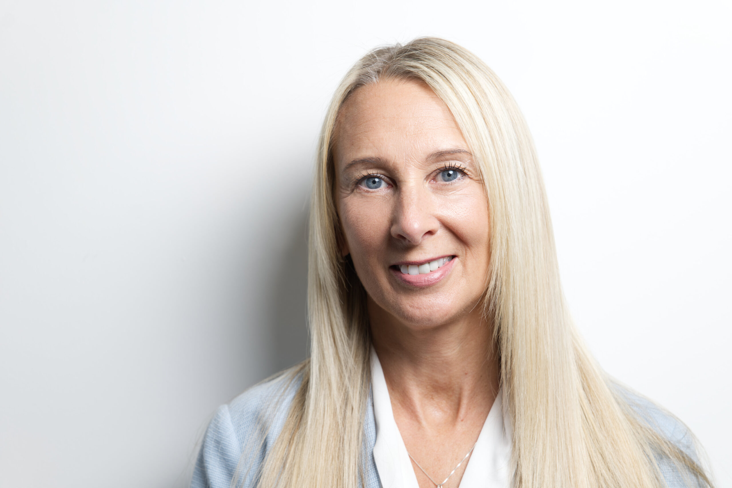 Professional headshot of a woman in front of a white wall