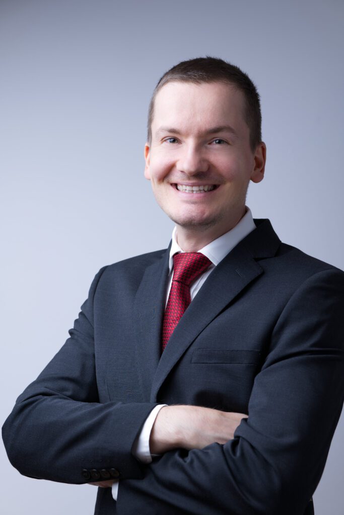 Smiling and friendly headshot of a man wearing a suit against a light backdrop - a Medway photographer who can capture this style of corporate headshots