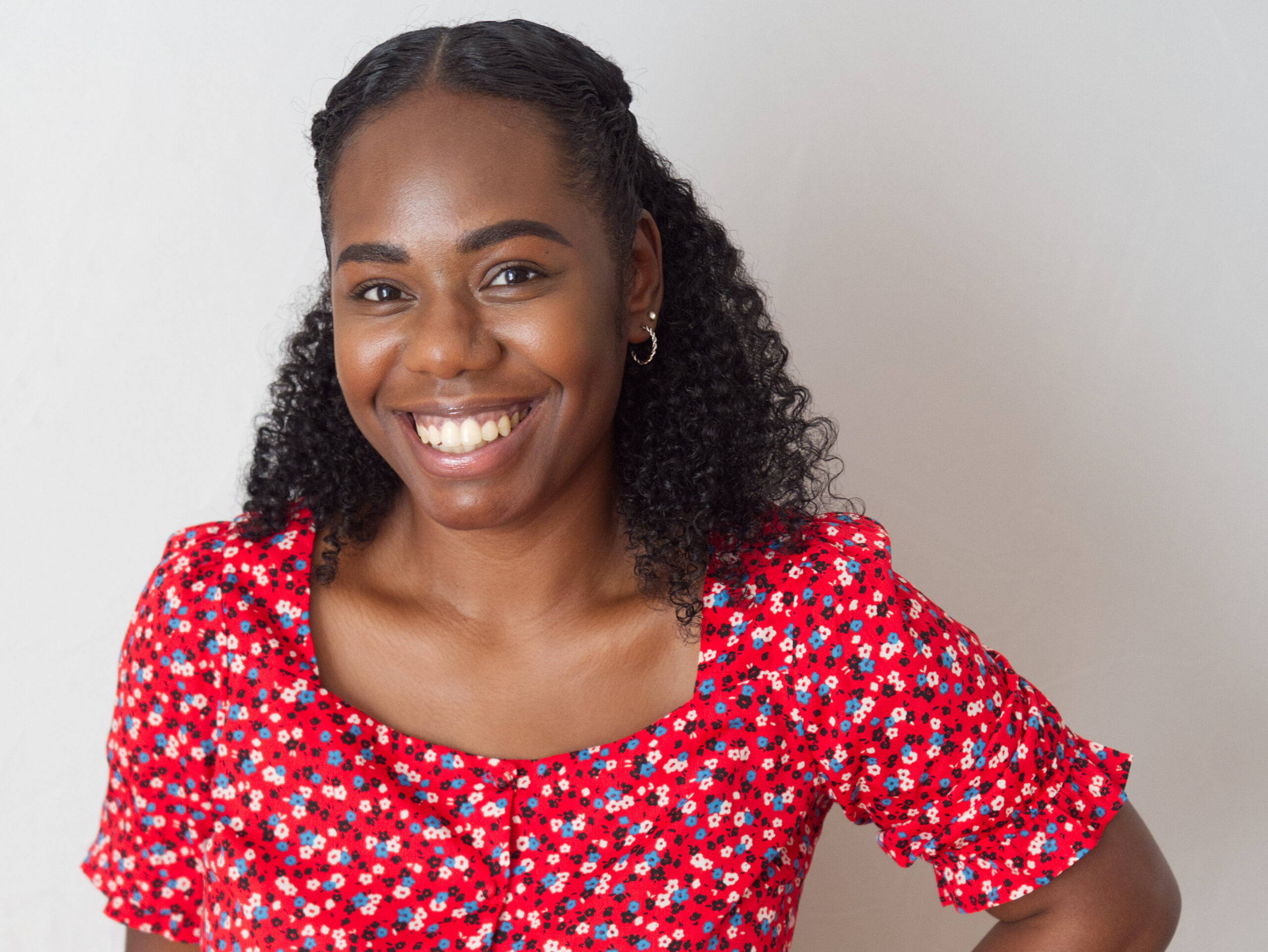 Portrait of a dark skinned woman wearing a flowery red top, taken by a headshot photographer in Kent