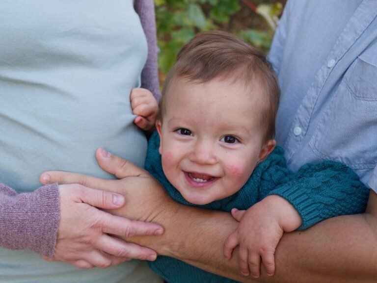 Family photographer Kent Toddler held by his mum and dad smiling at the camera during a family photoshoot